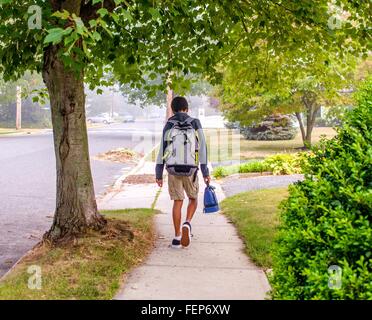 Junge mit Rucksack zu Fuß auf dem Bürgersteig Stockfoto