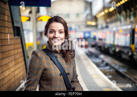 Junge Frau in braunen Wintermantel warten am Bahnhof Stockfoto