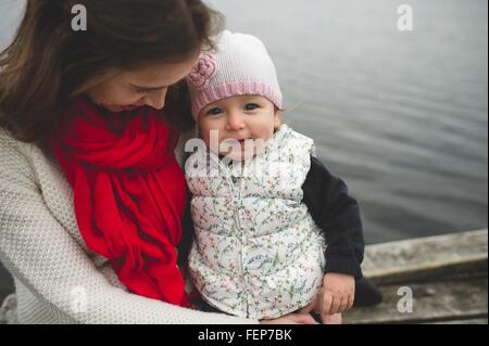 Mutter und Tochter sitzen zusammen am Steg Stockfoto