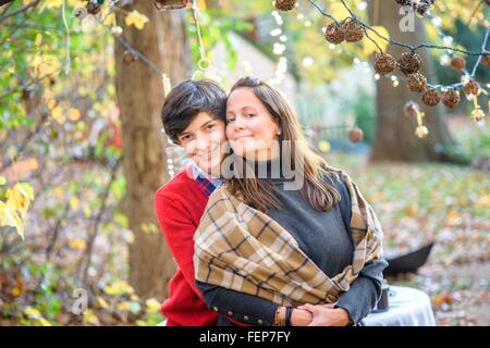Porträt von Teenager-Sohn umarmt Mutter im Wald Stockfoto