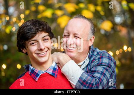 Porträt von reifer Mann mit Händen auf Söhne im Teenageralter Schulter im Wald Stockfoto