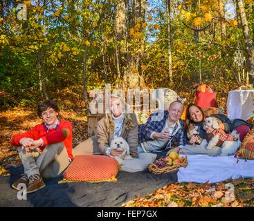 Porträt des reifes Paar mit Hunden, Teenager und Erwachsene Kinder entspannen Sie sich auf der Picknickdecke im Wald Stockfoto