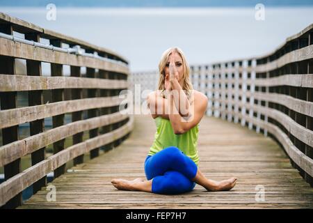 Porträt der jungen Frau praktizieren Yoga pose auf hölzerne pier Stockfoto