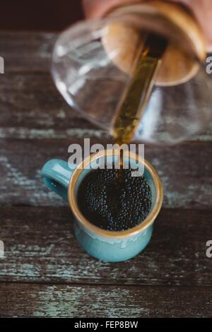 Man gießt Kaffee aus der Kaffeemaschine Stockfoto
