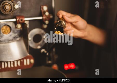 Mann, der Kaffeebohnen in Kaffeeröster, Nahaufnahme Stockfoto