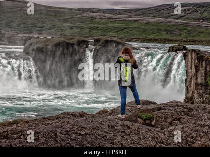 1. August 2015 - BáRðArdalur District, North Central Island, berühmt Island - eine weibliche Touristen Fotografien der hufeisenförmige doppelten Wasserfall von Goðafoss von der Westbank. Einer der spektakulärsten und schönsten Wasserfälle in Island, auf dem Fluss Skjálfandafljót, sein Name ist Wasserfall der Götter aus der Legende des dann Lawspeaker Porgeir wirft seinen nordischen Gott Statuen in den Wasserfall in einem symbolischen Akt der Bekehrung des Island zum Christentum im Jahr 1000. Der Tourismus ist ein wachsender Sektor der Wirtschaft geworden und Island ist ein beliebtes Touristenziel geworden. (Bild Kredit: Stockfoto