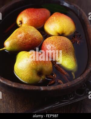 Seckel Birnen mit Zimtstange und Sternanis in Vintage hölzerne Schüssel mit Wasser Stockfoto