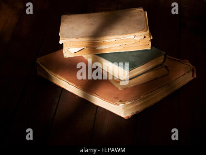 einige alte zerfetzt, lesen Sie Bücher über Holztisch auf das Licht vom Fenster fällt Stockfoto