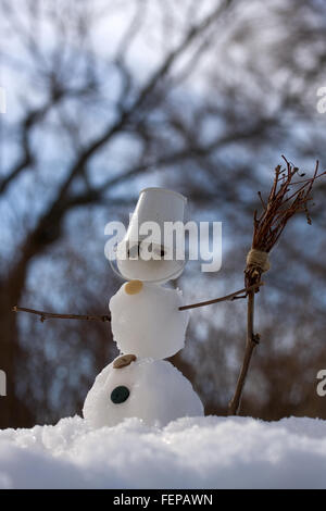 kleine Schneemann in den Eimer statt Hut auf dem Kopf mit Besen Stockfoto