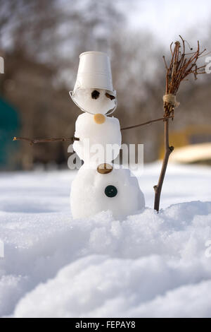 kleine Schneemann in den Eimer statt Hut auf dem Kopf mit Besen Stockfoto