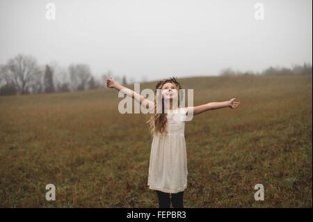 Porträt von langen blonden Haaren Mädchen mit offenen Armen in Feld Stockfoto