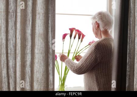 Ältere Frau arrangieren Blumen in Vase, Rückansicht Stockfoto