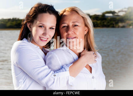 Eine Reife blonde Mutter posiert mit ihrer schönen griechischen aussehende Tochter an den Ufern des Flusses in Südafrika. Ihre Liebe Stockfoto