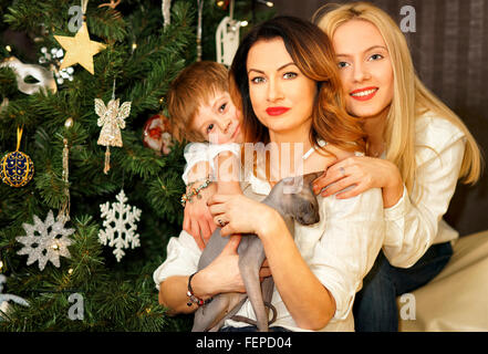 Schöne Familie bestehend aus Mutter, Tochter und Sohn in der Nähe von Weihnachtsbaum. Mutter hält Sphinx Katze. Stockfoto