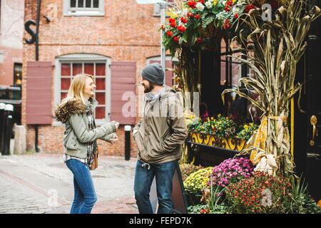 Junges Paar im Chat auf gepflasterten Straße außerhalb Floristen, Boston, Massachusetts, USA Stockfoto