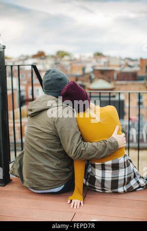 Junges Paar sitzt mit Blick vom Stadt-Dachterrasse Stockfoto