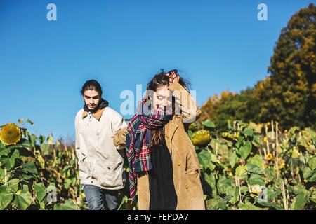 Junges Paar Spaziergang durch Feld von Sonnenblumen Stockfoto