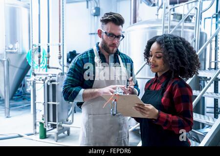 Kolleginnen und Kollegen im Blick auf Zwischenablage lächelnd Brauerei Stockfoto