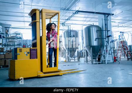 Mitte erwachsenen Frau in Brauerei fahren Gabelstapler wegschauen Stockfoto