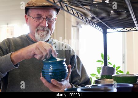 Blick durch die Regale von Potter Blick auf glasierten Tontopf mit Deckel Stockfoto