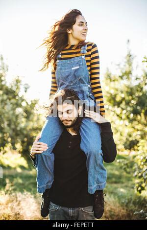 Junges Paar in der ländlichen Umgebung, junge Frau sitzt auf den Schultern des Mannes Stockfoto