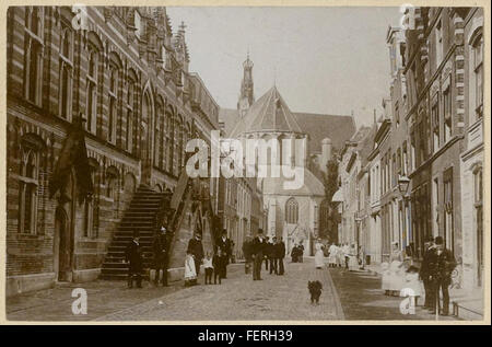Ein Foto aus der Zeit um 1890, das die Langestraat in Alkmaar zeigt, mit bemerkenswerten Wahrzeichen wie der Grote Kerk (große Kirche) und Stadhuis (Rathaus), die einen Einblick in die historische Architektur der Stadt bieten. Stockfoto