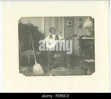 Dieses Bild zeigt eine afroamerikanische Jugend, die das Banjo spielt, ein Schlüsselinstrument in der Entwicklung der amerikanischen Folk- und Bluesmusik. Das Banjo hat eine bedeutende kulturelle Bedeutung in der afroamerikanischen Musiktradition. Stockfoto