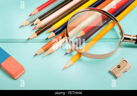 Lupe mit bunten Bleistift auf blauen Holztisch Stockfoto