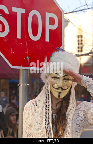 Asheville, North Carolina, USA - 7. Februar 2016: Frau trägt einen Darm Fawkes Maske Symbol der Rebellion steht neben einem Stop-Schild und salutiert während einer Karneval Parade am 7. Februar 2016 in der Innenstadt von Asheville, North Carolina-Credit: Judith Bicking/Alamy Live News Stockfoto