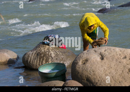 Filipino junge wäscht Kleidung am Ufer des Flusses, Negros Occidental. Stockfoto