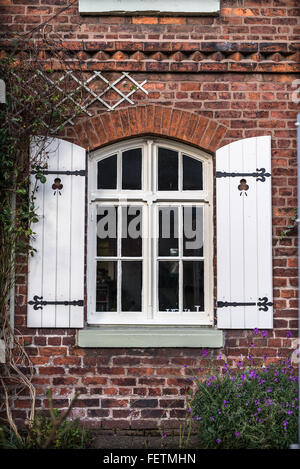 Aus rotem Backstein Ferienhaus mit hölzernen Fensterläden und Vorgarten. Stockfoto