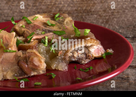 Nahaufnahme von Sülze Schweinefleisch - Aspik auf rotem Teller Stockfoto