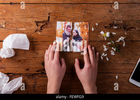 Nicht erkennbare traurige Frau hält zerrissenes Bild des Paares in der Liebe. Stockfoto