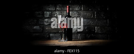 Flasche und Glas Wein in der Nähe von schwarzen Wand Stockfoto