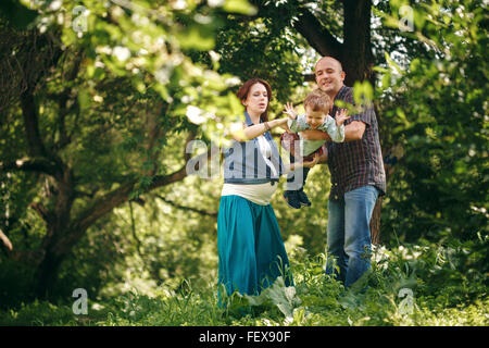 Glückliche junge Eltern mit ihrem Sohn im Park spielen. Familie Kleidungsstil. Natürliche Farben. Stockfoto