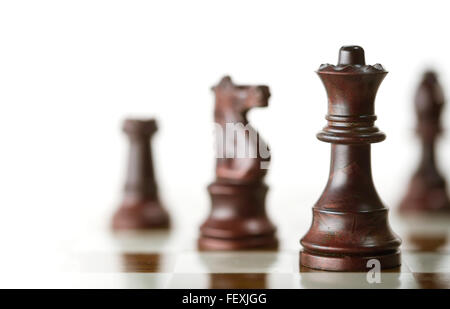 Horizontale Bild von ein Schachspiel mit Fokus auf die Königin und eine verschwommene Stücke über weißen Hintergrund, Kopieren Raum auf der linken Seite. Stockfoto