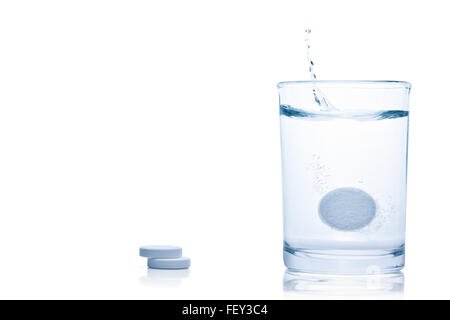 Fizzy Pille Spritzer in ein Glas Wasser, isoliert auf weißem Hintergrund, Schneidepfad enthalten. Stockfoto