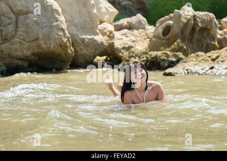 schönes glückliches Mädchen spielen im Meer zwischen den Wellen Stockfoto