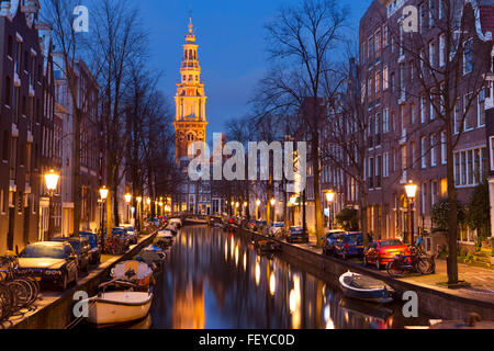Ein Kirchturm am Ende eines Kanals in der Stadt Amsterdam, die Niederlande in der Nacht. Stockfoto