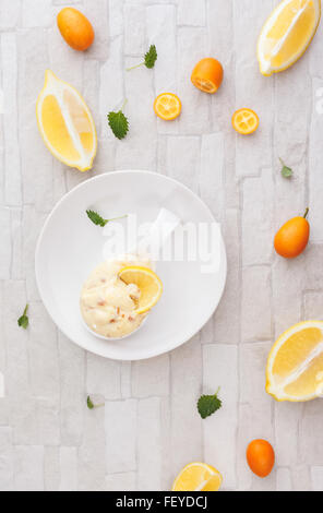 Zitrusfrucht-Mousse. Hausgemachte Zitronen Mandel Mousse mit kandierten Kumquats Schale. Draufsicht, Leerzeichen, rustikaler Hintergrund Stockfoto