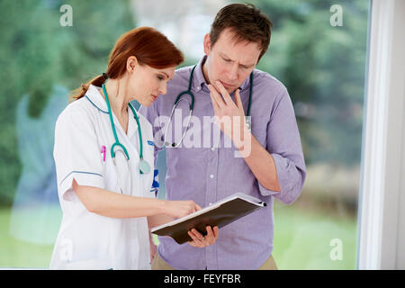 Arzt und Krankenschwester diskutieren Notizen Stockfoto