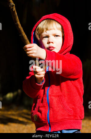 Kleiner Junge spielt im Wald mit einem Stock Stockfoto