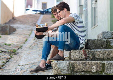 Angesagte Männer sitzen auf Stufen und halten skateboard Stockfoto