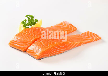 roher Lachs Filets mit Zitrone und Petersilie auf weißem Hintergrund Stockfoto