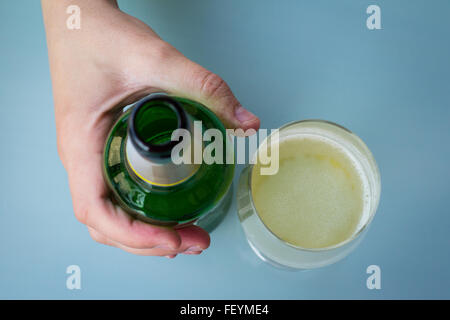 Hand halten, dass eine Bierflasche in der Nähe eine halbe Bierglas gefüllt Stockfoto