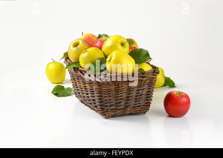 Korb mit roten und gelben Äpfeln auf weißem Hintergrund Stockfoto