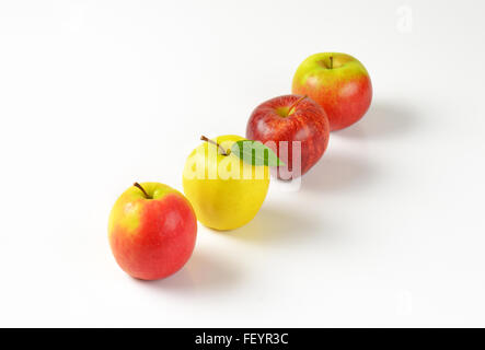 vier Reifen Äpfeln in einer Reihe auf weißem Hintergrund Stockfoto