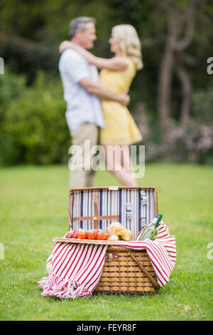 Glückliches Paar umarmt neben Picknick-Korb Stockfoto