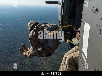 Ein Soldat der US-Armee springt aus einem UH-60 Black Hawk während der 18. jährliche Randy Oler Memorial Betrieb Spielzeug fallen, moderiert von US Armee zivile Angelegenheiten & psychologische Operations Command (Airborne) in Camp Mackall, North Carolina, 8. Dezember 2015. Betrieb Spielzeug Drop ist der weltweit größte Luft Mischbetrieb, die Fallschirmjäger aus den USA und sieben Partnernationen die Möglichkeit bietet, Kinder Spielzeug für den Urlaub zu erhalten helfen. Stockfoto