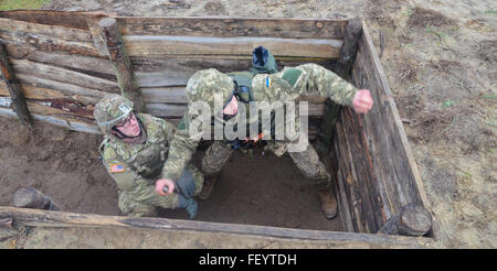 Ein Fallschirmjäger mit der 173rd Airborne Brigade (links), coacht und Uhren ein Soldat mit der ukrainischen Landstreitkräfte (rechts), 10. Dezember 2015, während des Trainings auf eine Handgranate im Rahmen des furchtlosen Guardian II der internationalen Friedenssicherung Security Center einzusetzen. Soldaten mit der ukrainischen Armee lernen richtige richtigen Griff und Wurftechniken nutzen Sicherheitsvorkehrungen anwenden. Stockfoto